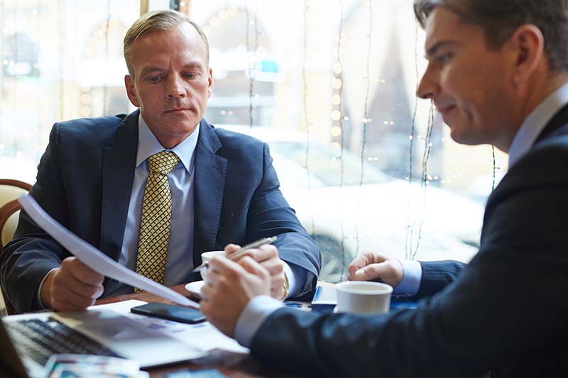 Two businessmen review their business process over coffee at a diner