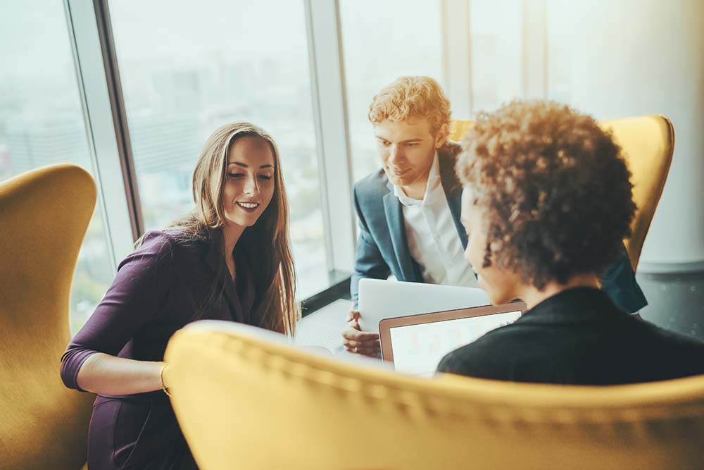 Two Foresee Now consultants work as a team to show client problem-solutions during office business meeting