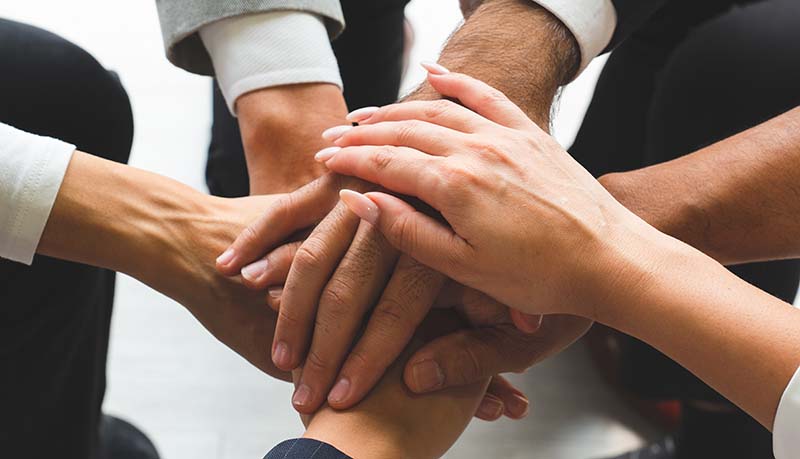 Six Foresee Now consultants put their hands in for a team cheer for supporting you