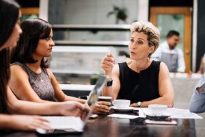 Four female Foresee Now specialists discuss crisis resolution strategies during team meeting in office